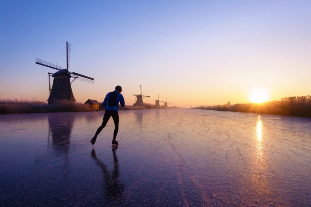 Ice skating on the canals of Kinderdijk among historical windmills